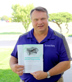 Tim Bower, computer systems technology professor at Kansas State Polytechnic for 12 years, holds his published article on robotics programming for beginners in the IEEE Robotics and Automation magazine.