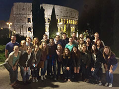 The study abroad group pauses for a picture in front of the Colesseum in Rome