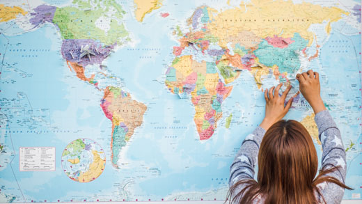 Girl places pin on world map.