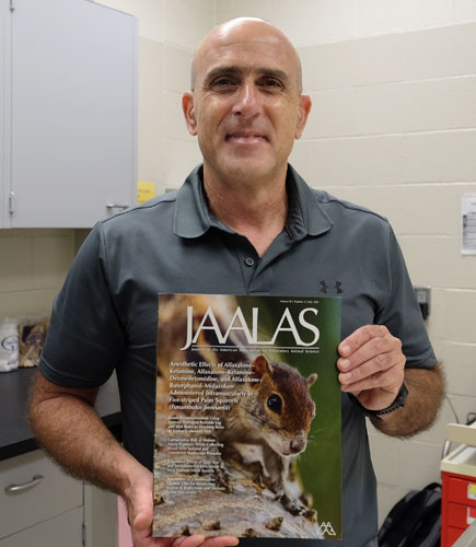 Dr. David Eshar holds the new issue of the Journal of the American Association for Laboratory Animal Science