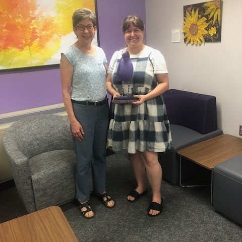 Emily Miner (right) receives the Purple Reign trophy