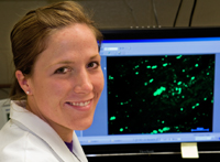 Randi King in front of computer screen showing a slide from her research