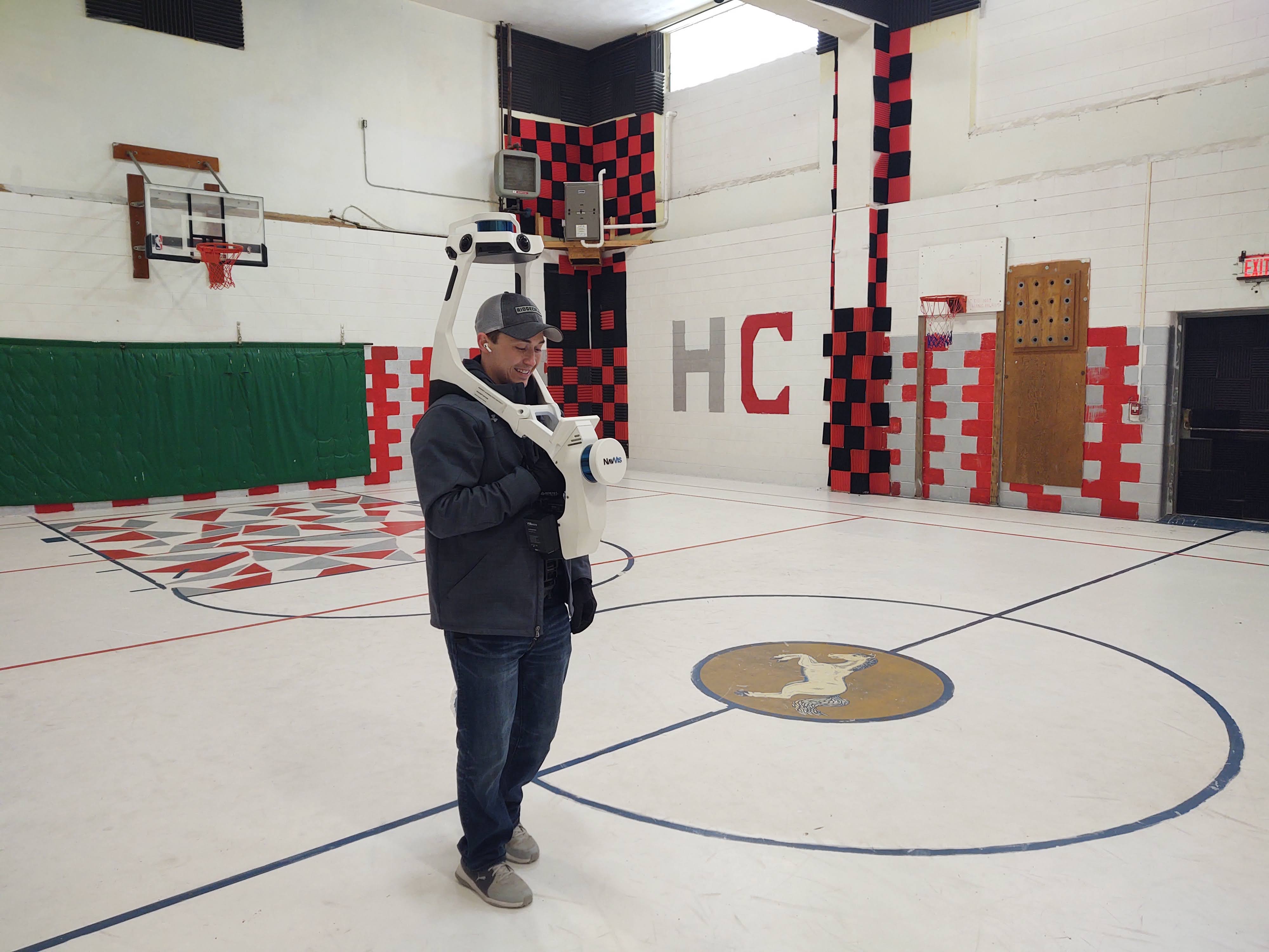Jacob Picolet, senior engineer with the Technology Development Institute at Kansas State University, uses a shoulder-mounted NavVis VLX digital scanning system to image the interior of the Memorial School Building in Hill City.