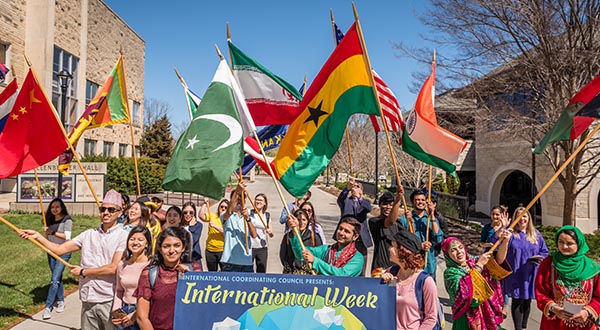 Students carrying a variety of country flags from all over the world