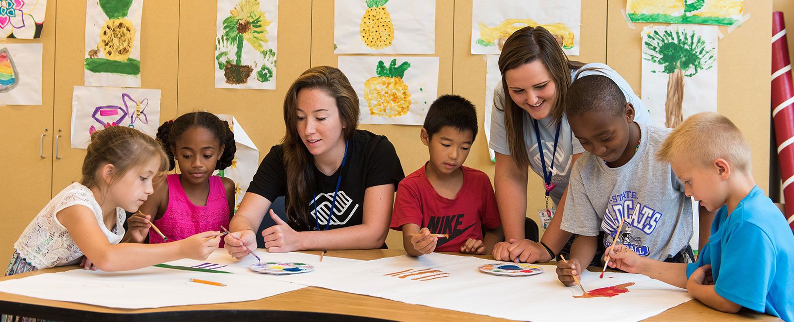 College students painting with children.