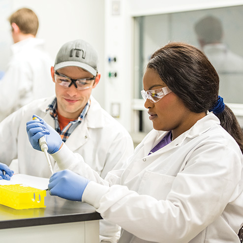 Two engineering students work together to draw samples in a studio classroom setting.