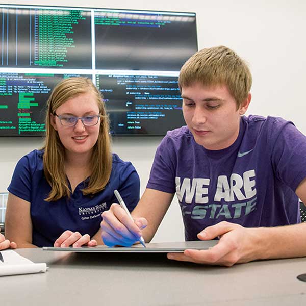 Two engineering students work together on a tablet in a studio classroom setting.