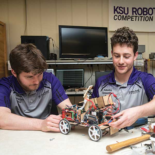 Two engineering students work together to build a piece of equipment in a studio classroom setting.