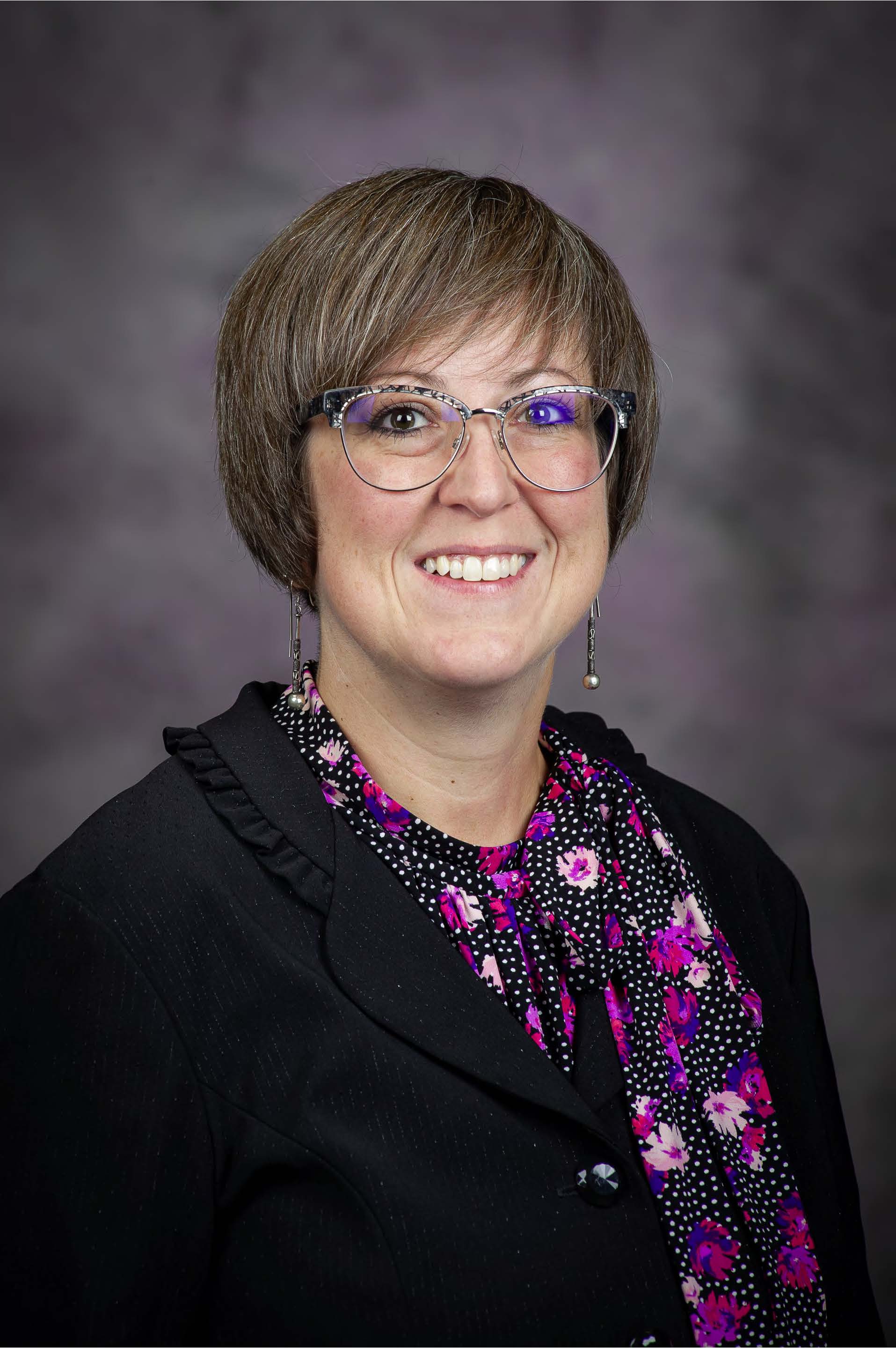 Photo of Lindsay Kubina in a dark suite and floral shirt.