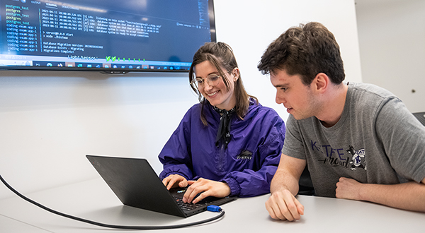 two students leaning over a computer together