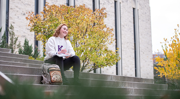 a student sitting on the steps of chalmers hall with a notebook