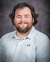 a bearded man in a grey polo
