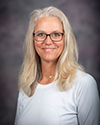 a woman with blonde hair and glasses in a white shirt