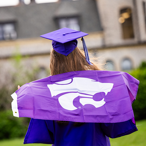 K-State graduate holding Powercat flag