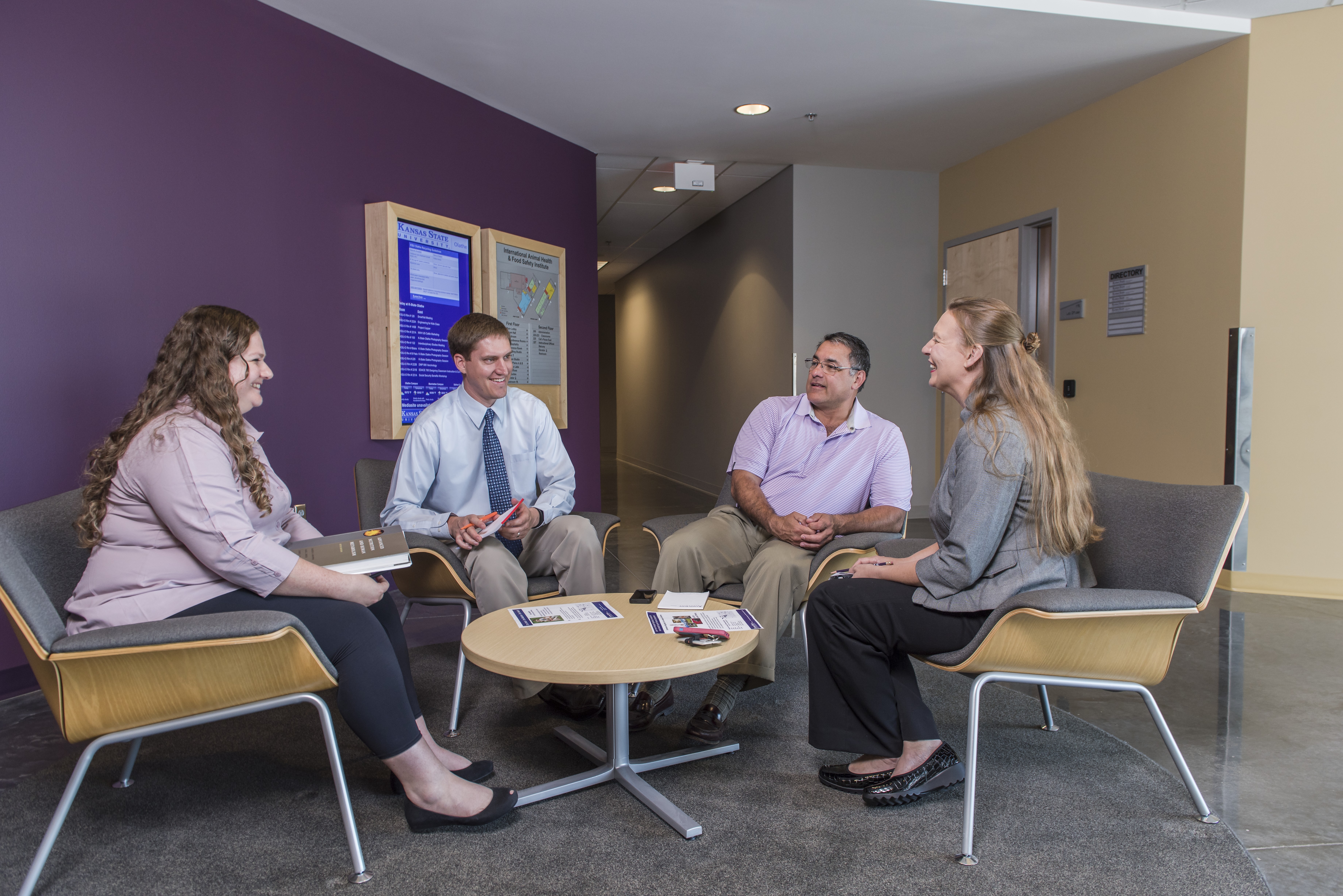A group of adults casually meet and talk around a small table.