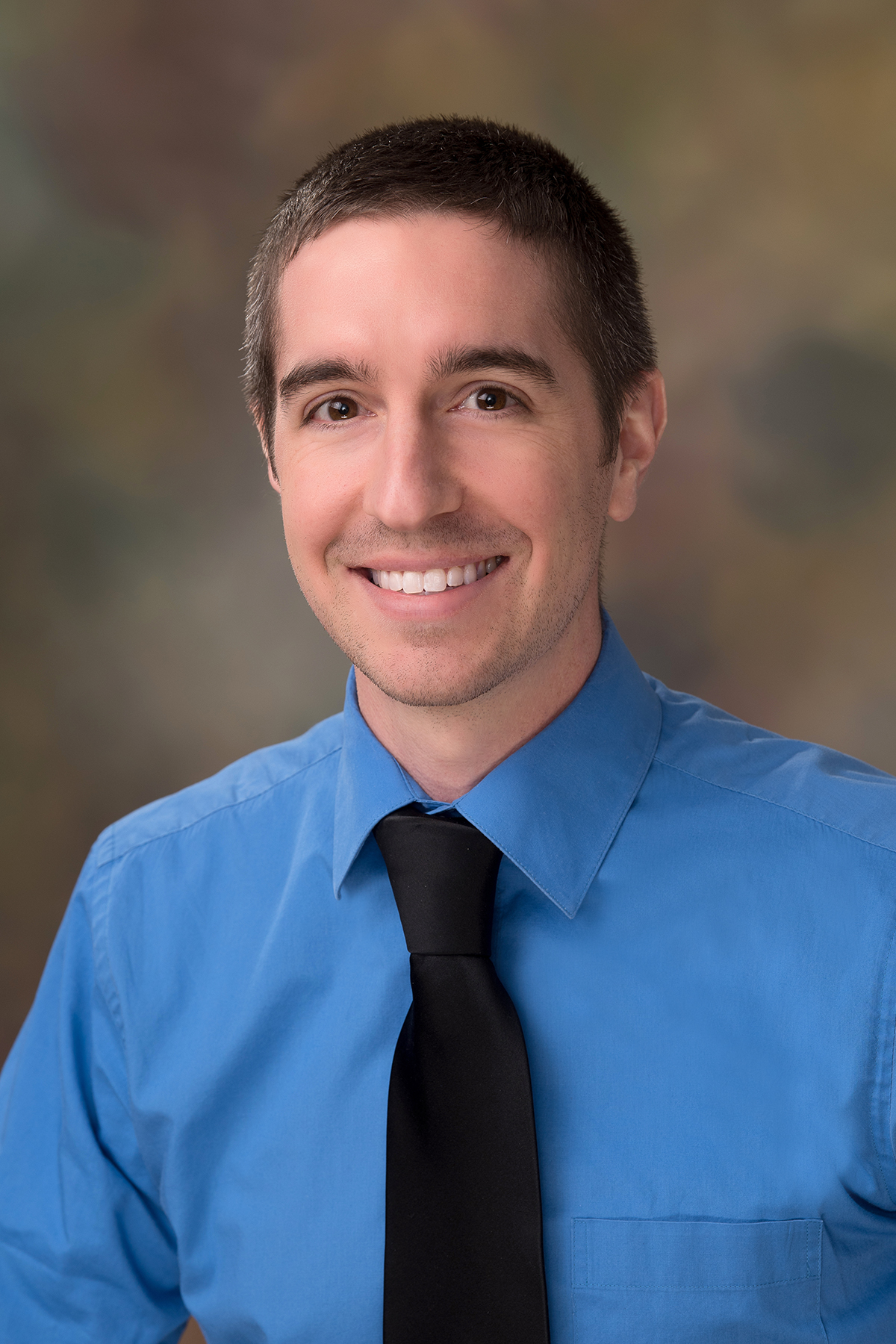 Photo of Jason Orr smiling in a blue dress shirt with a black tie.