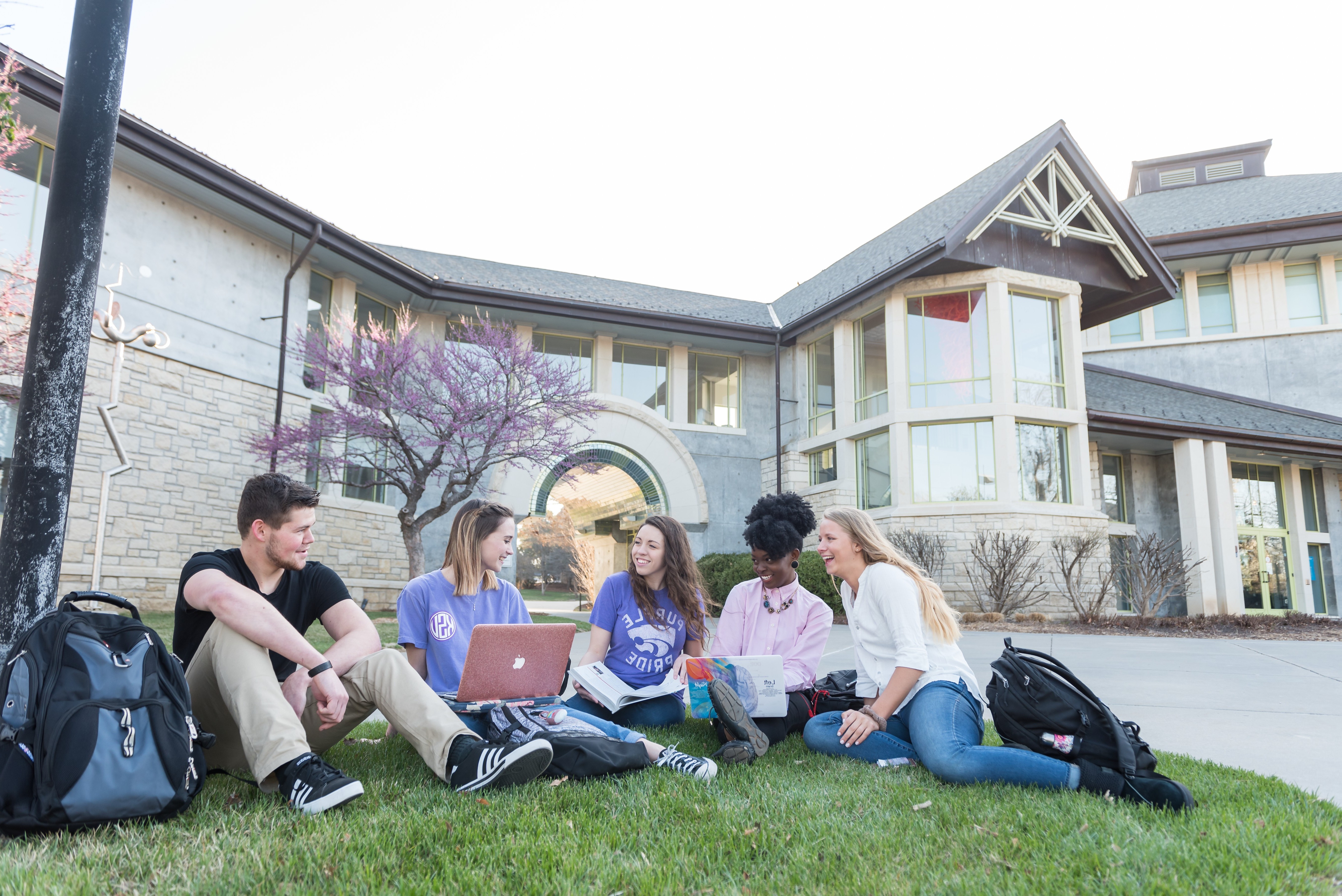 Four undergraduate students walking on campus, laughing and talking to one another.