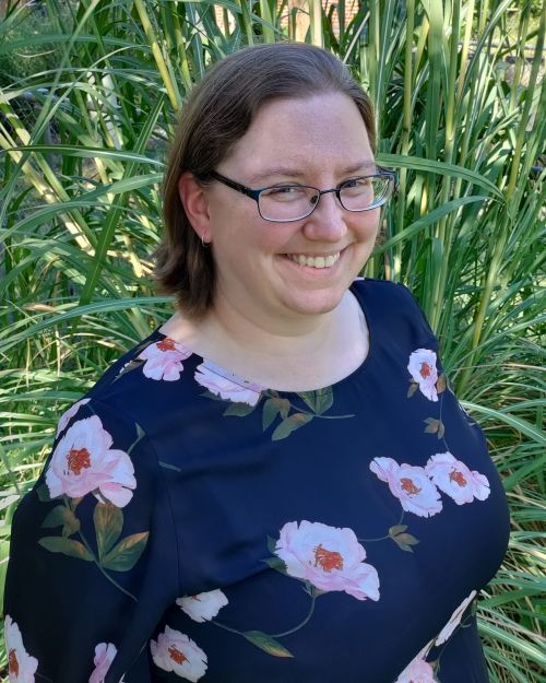 Virginia is wearing a blue blouse with large light pink flowers.