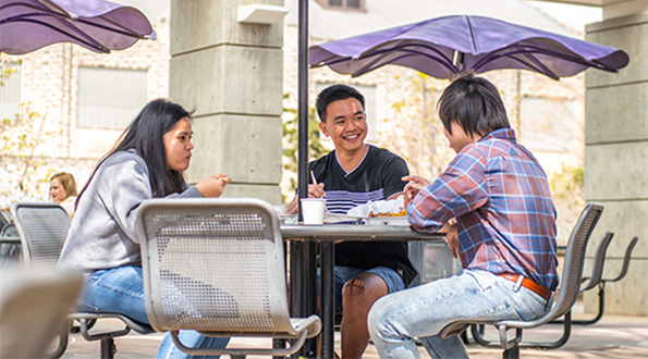 Student sitting around an outdoor table talking.