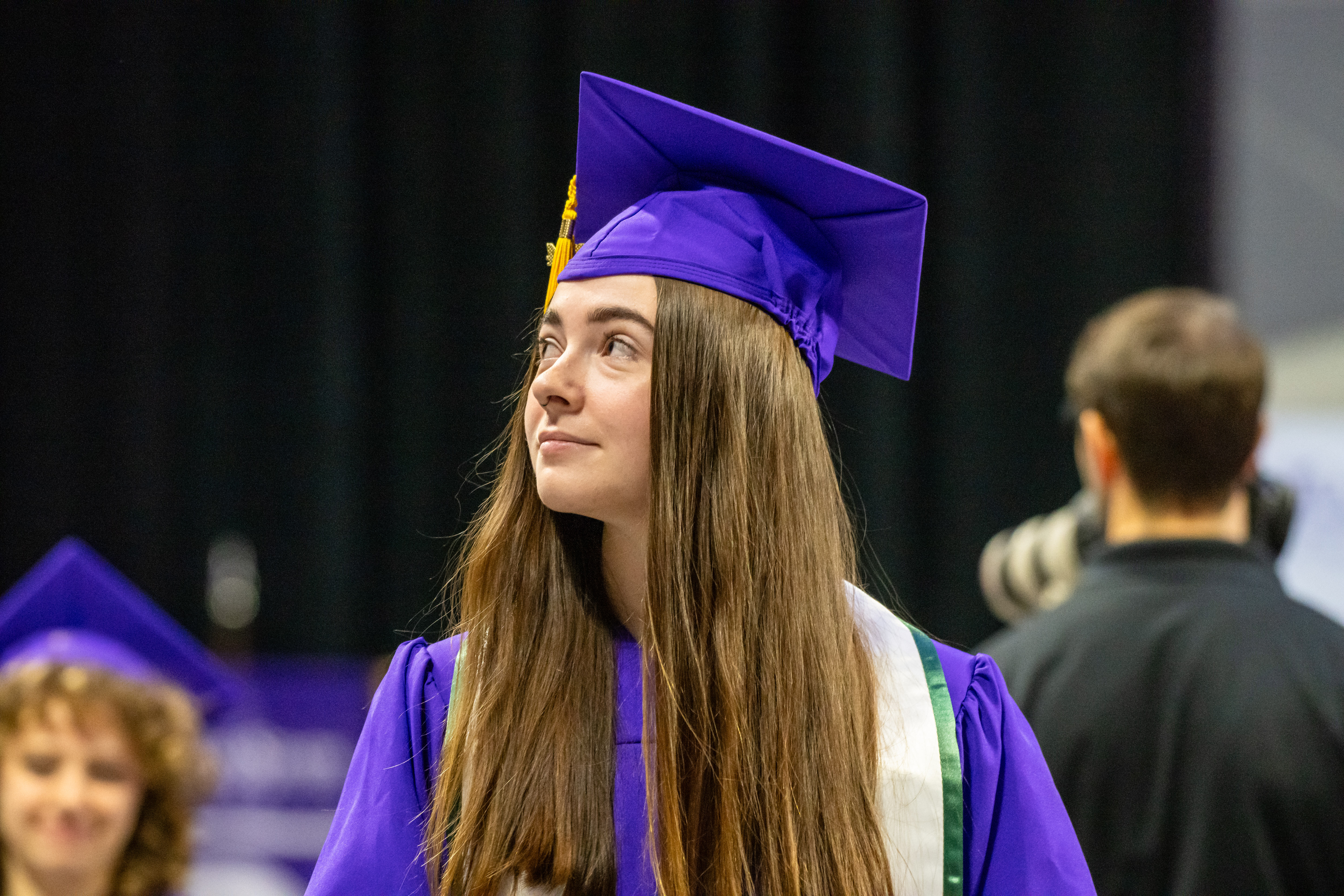 Student walking with a purple graduation cap and gown.