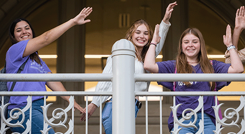 Three K-State students pose while making the letters K-S-U with their arms.