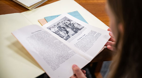 Woman looks at an old brochure filed in a manila folder.