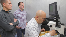 Image of Dr. Brian Geisbrecht overseeing research with lab staff and link to Dr. B. Geisbrecht's YouTube research video