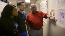 Image of Dr. Kanost discussing research poster with students.