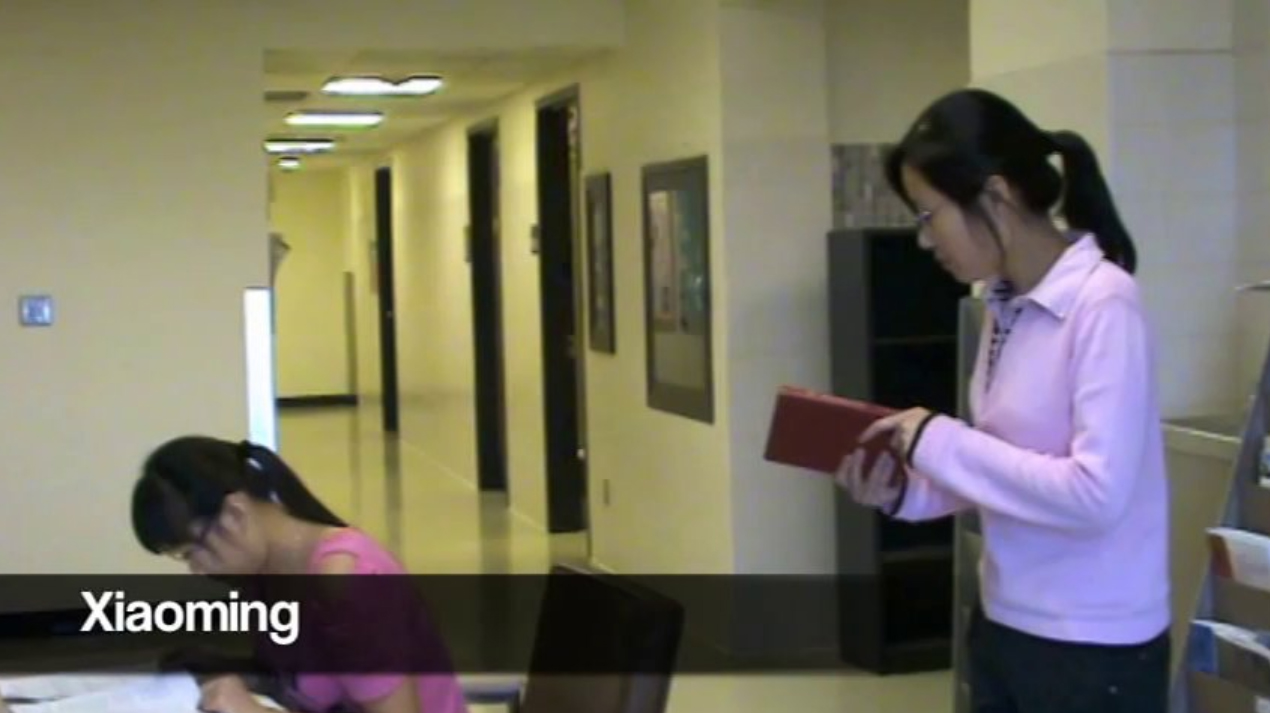 This is a screen grab of a video with two young ladies interacting around a book.