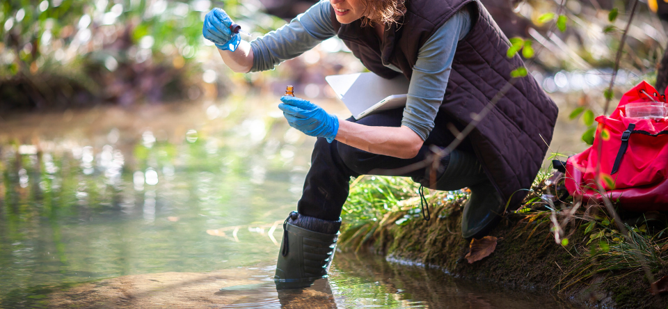 woman collecting water sample outside