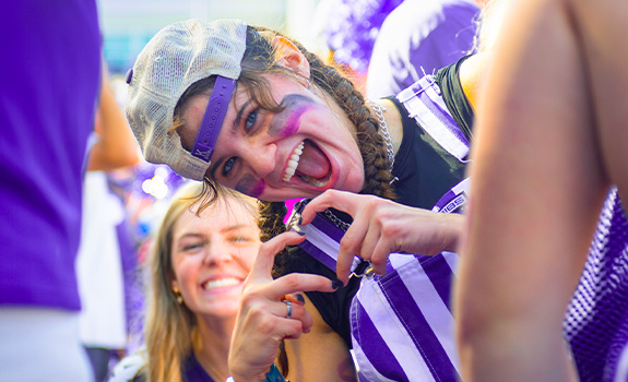 Student at a football game making a heart