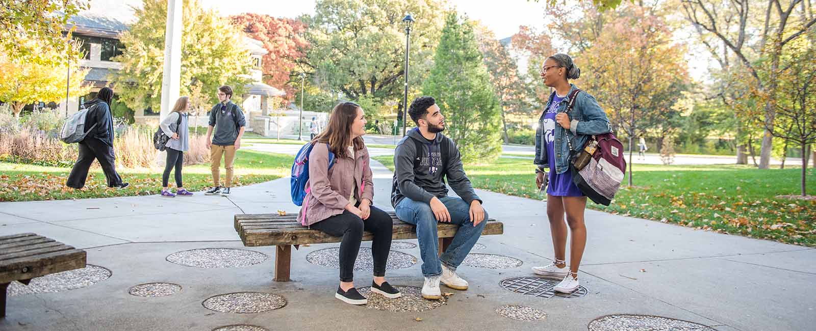 Students sitting on bench on K-State campus