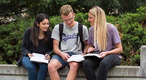 Students sitting on wall outside of campus building