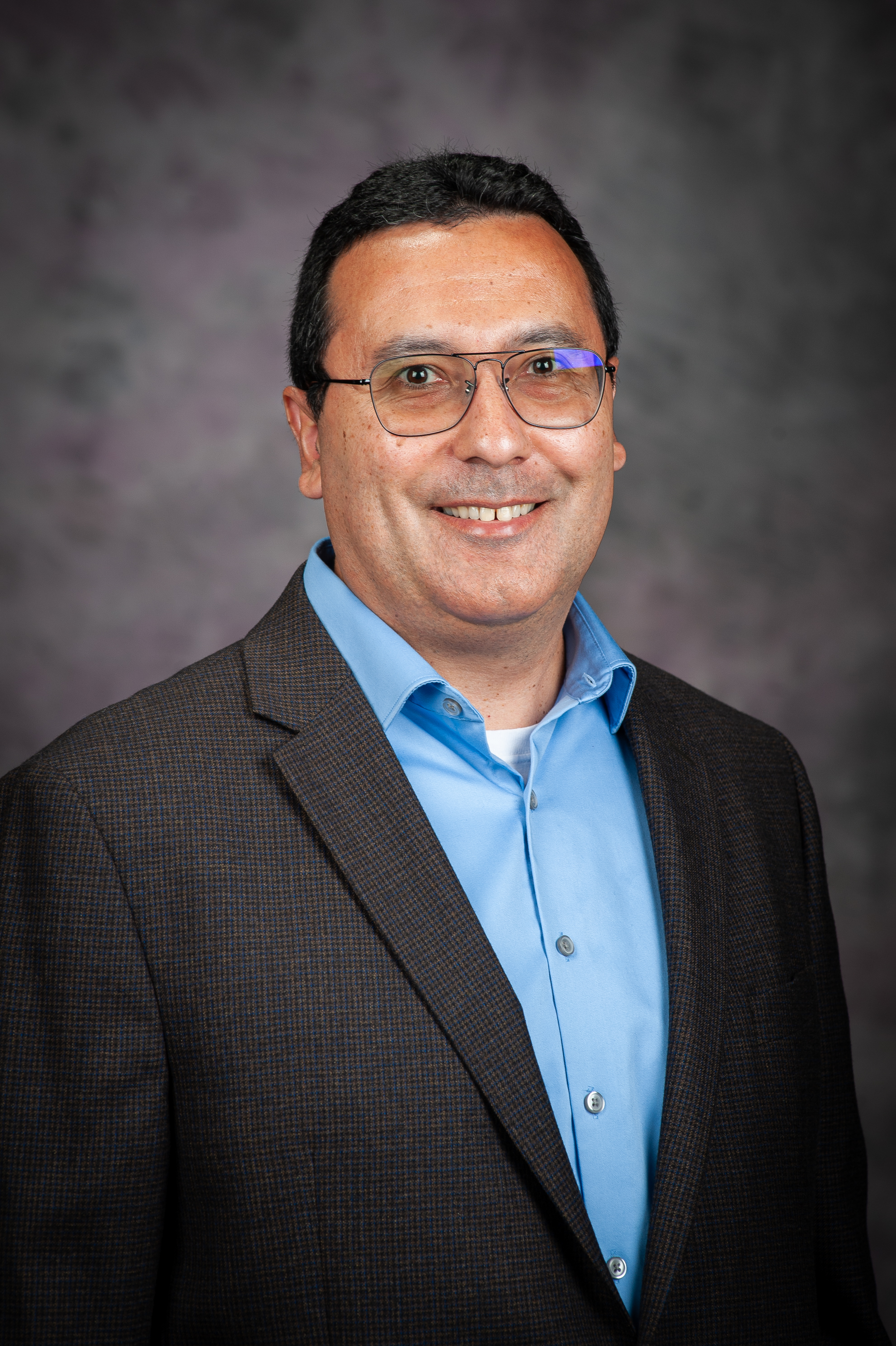 Portrait of a man in a suit jacket with glasses and a smile