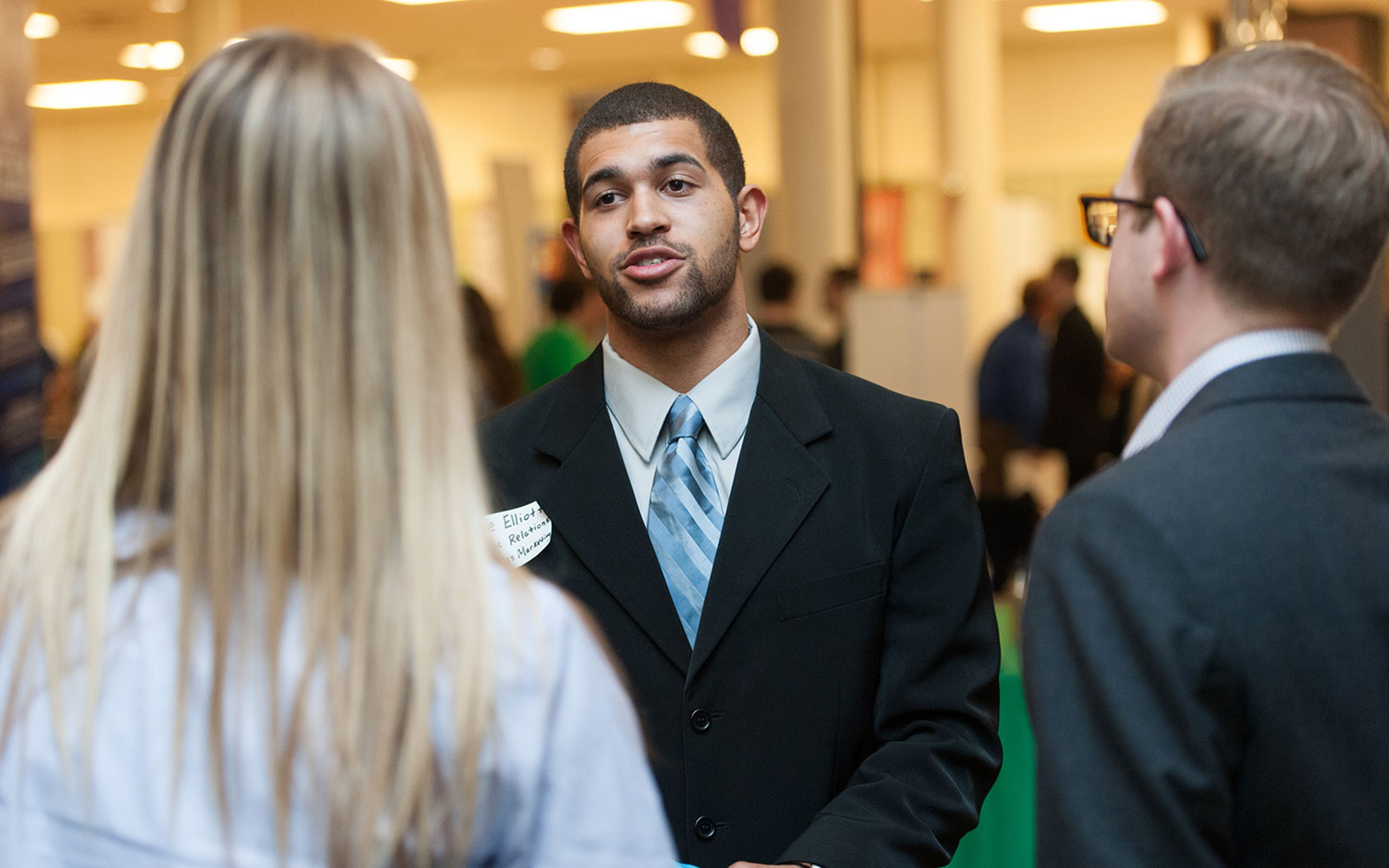 A student talks with two people at a career fair.