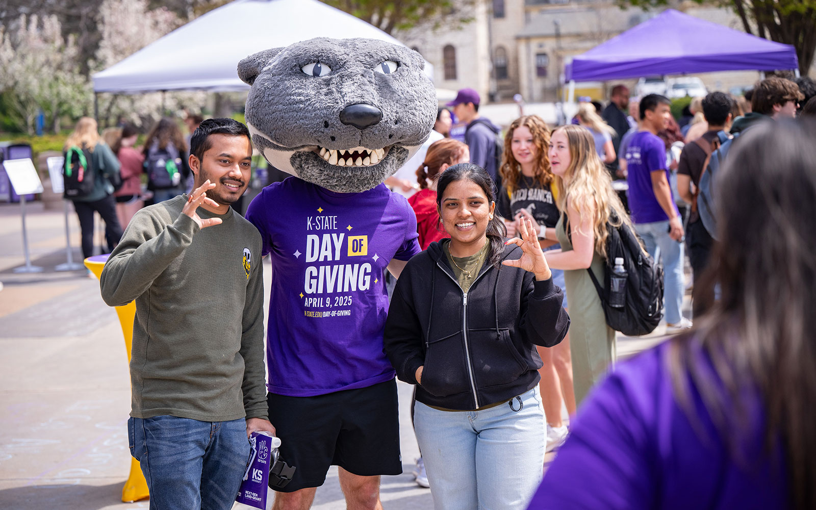 Two students smile with Willie Wildcat.