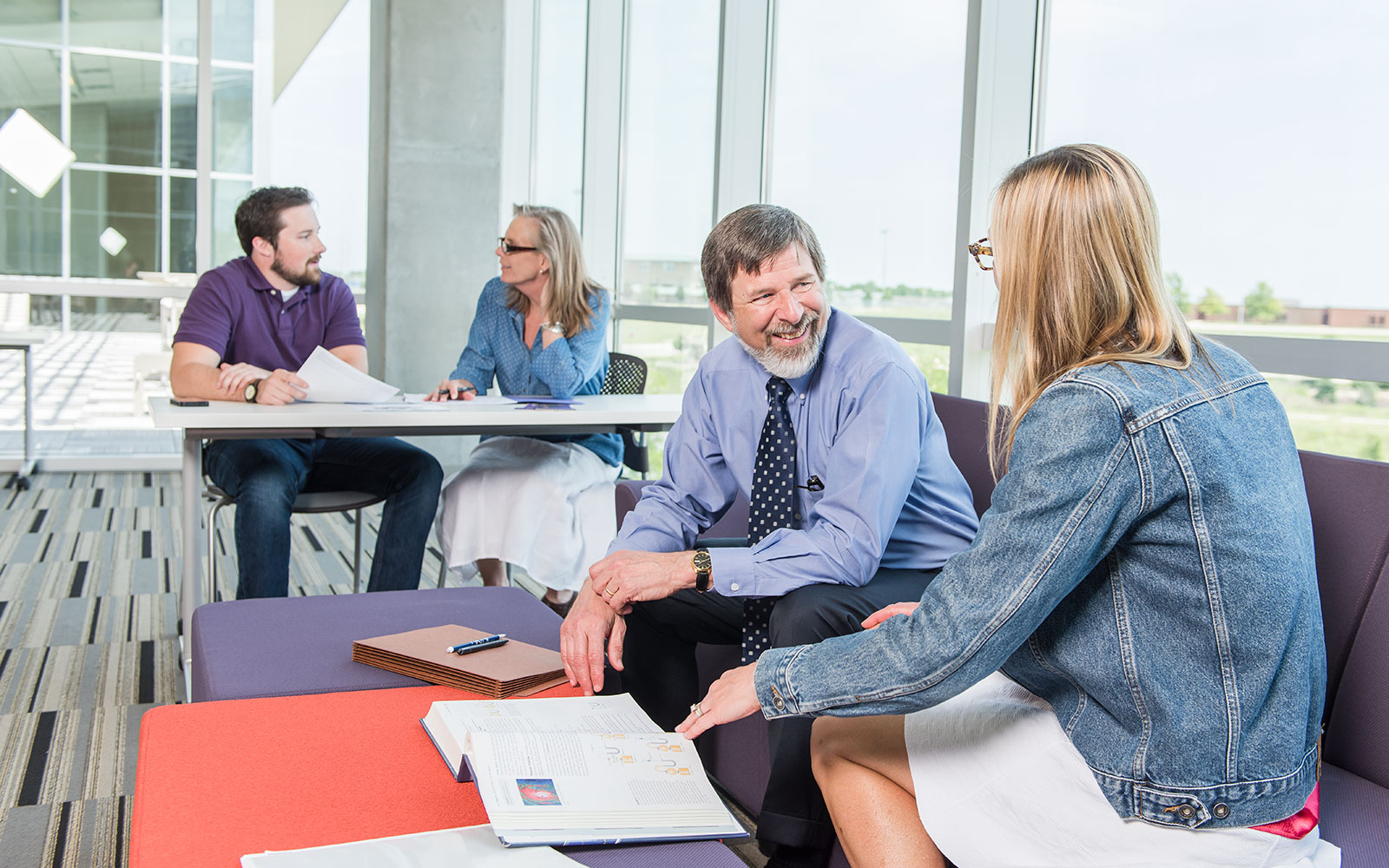Two faculty members meet with two students over textbooks.