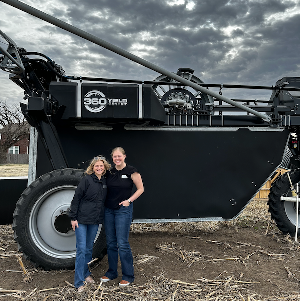 two student stand in front of a 360RAIN irrigation rig