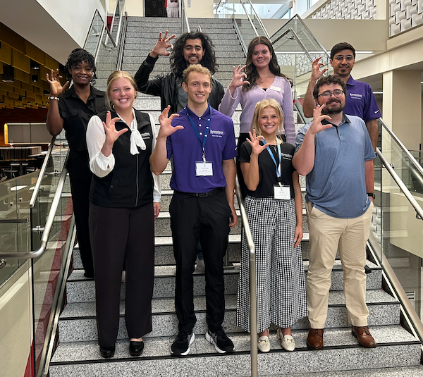 8 student Water Fellows gather to give the wildcat sign at a conference