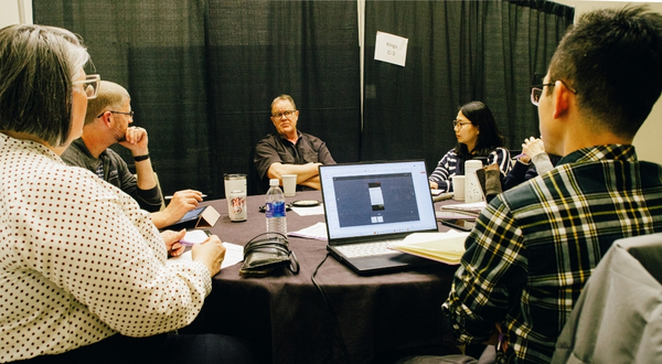 faculty sit around a table with computers to plan their research