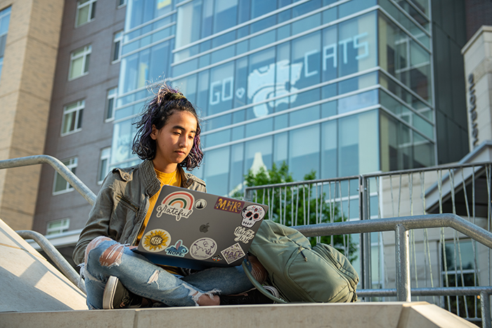 a student sitting outside on their laptop