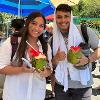 2 students enjoying a drink from some coconuts.