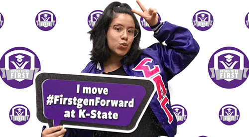 A student poses for a photo booth selfie, holding a sign that says "I move #firstgenforward at K-State
