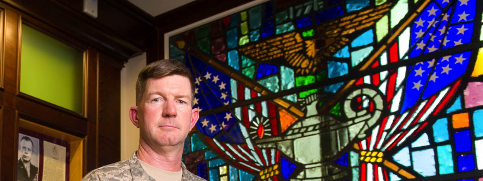 Uniformed man stands in front of stained-glass window