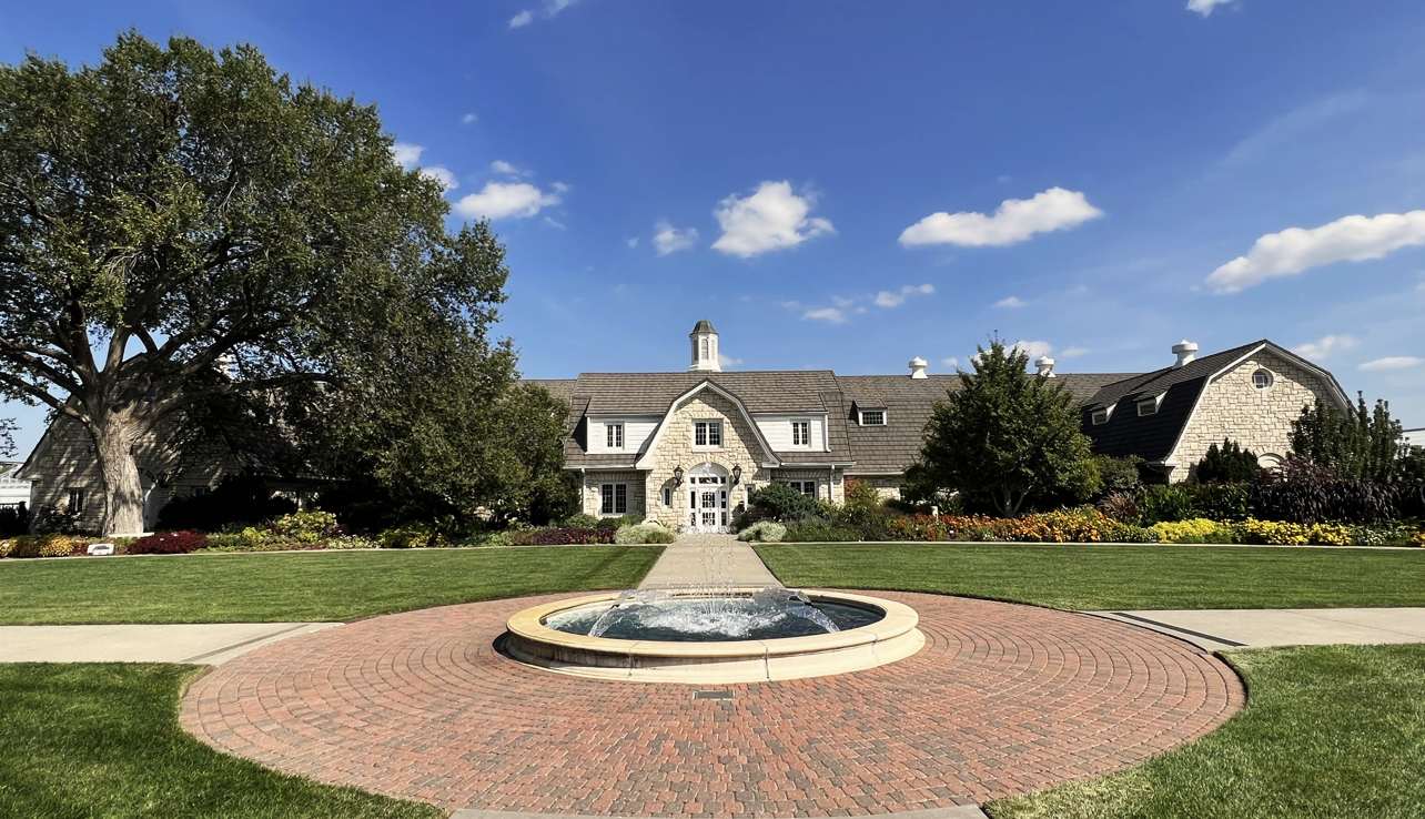 Background is a building with blue sky and clouds with a fountain flowing water upwards