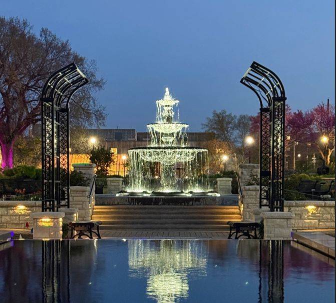 Three tier fountain with flowing water with reflection cast onto water in the foreground