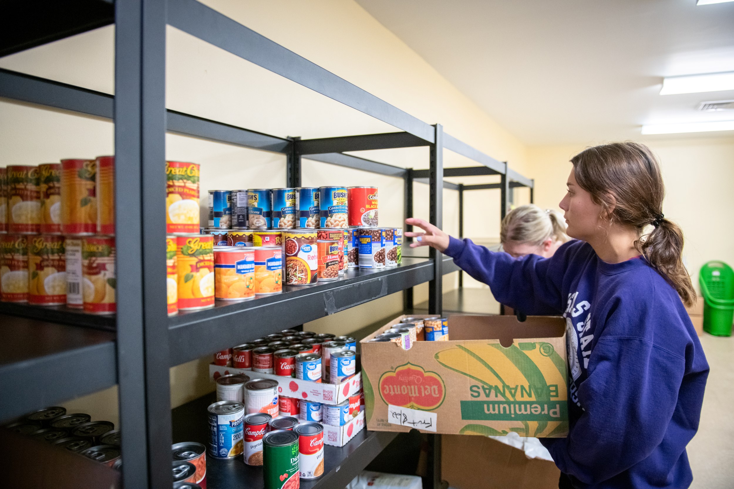 Student stocking food pantry shelves