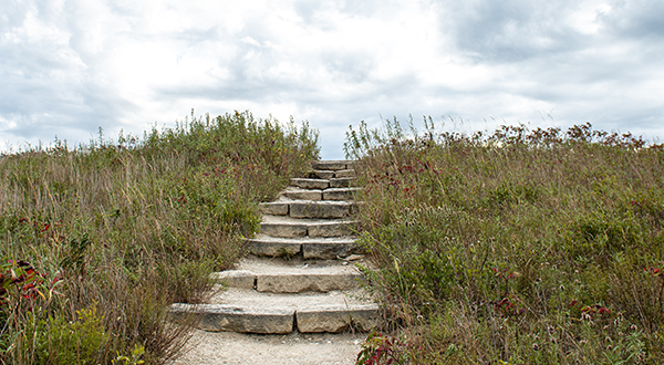 a stone path uphill towards a cloudy sky