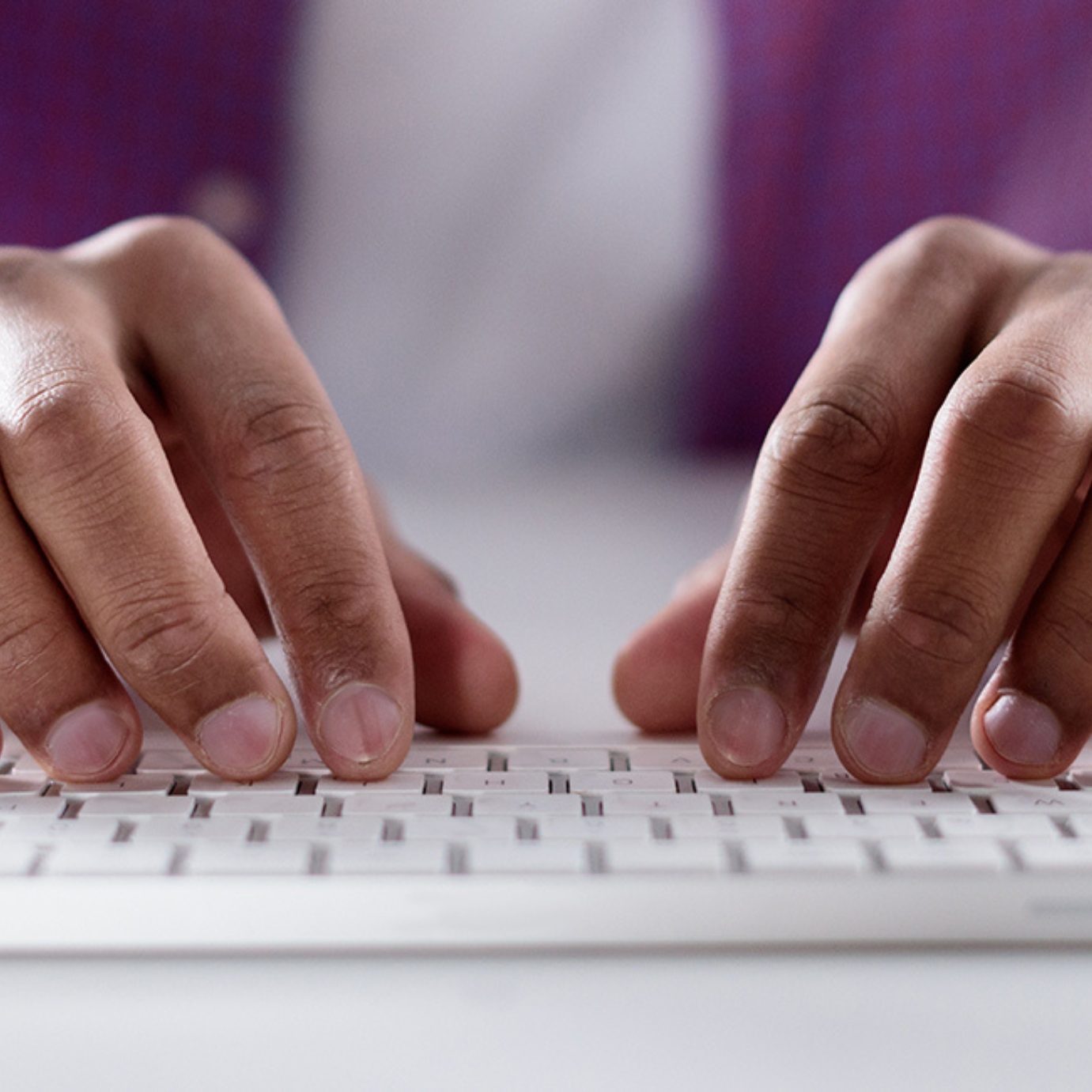 Two hands typing on a computer keyboard