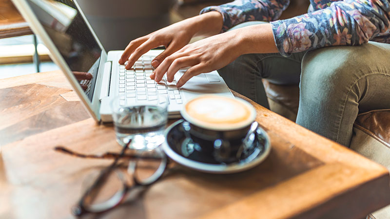 A person on their computer drinking tea.